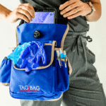 A clinician places a tablet into a blue TagBag medical field bag, with gloves and pens stored in front pockets.
