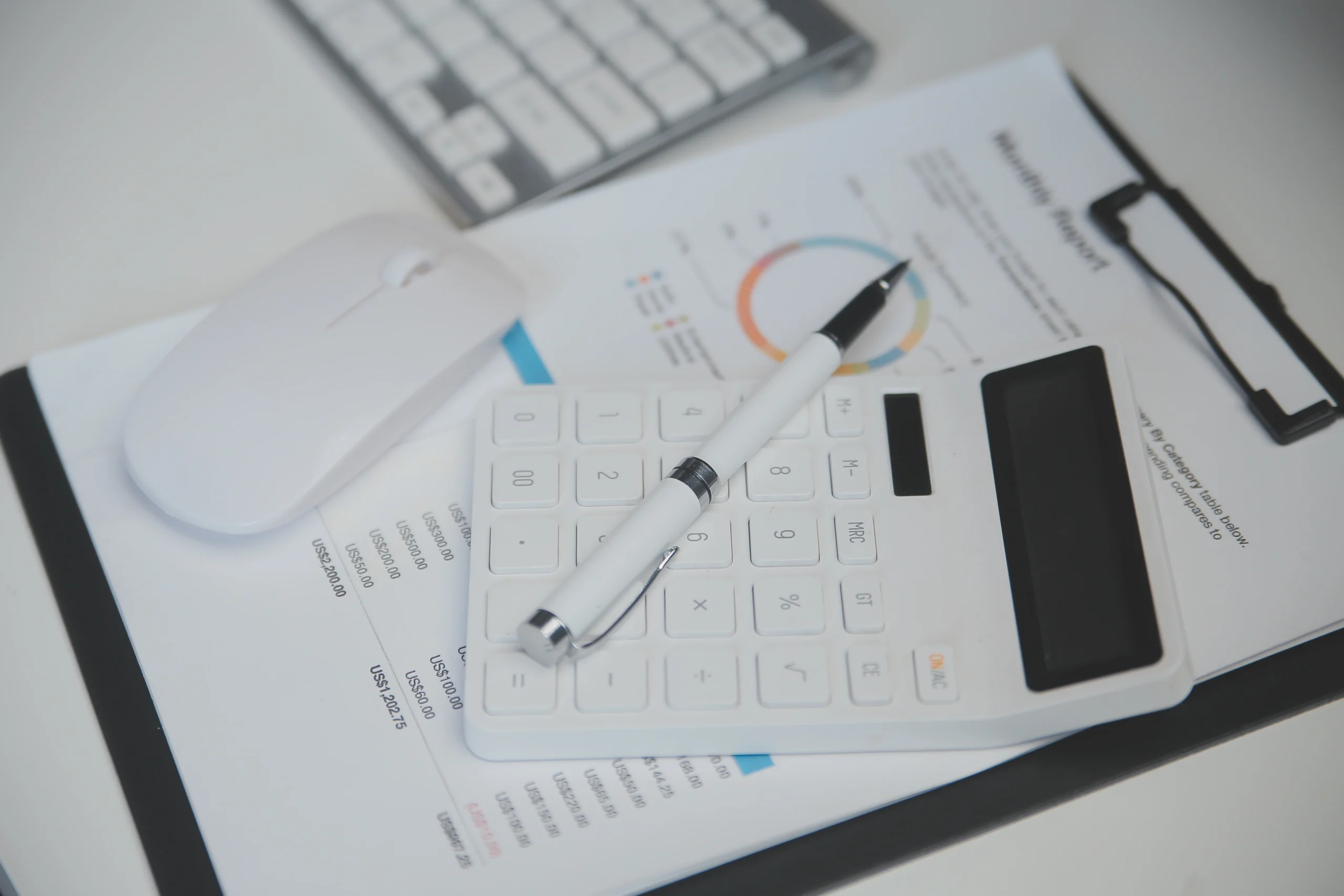 vecteezy_laptop-and-paperwork-on-conference-table_42628905 Close-up of a white calculator and pen resting on financial documents with a colorful chart in the background on a desk.